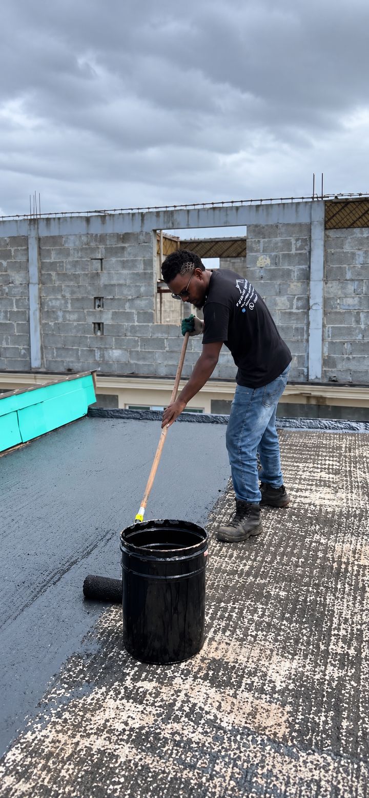 Ouvrier PTF appliquant le primer sur toute la surface de la toiture